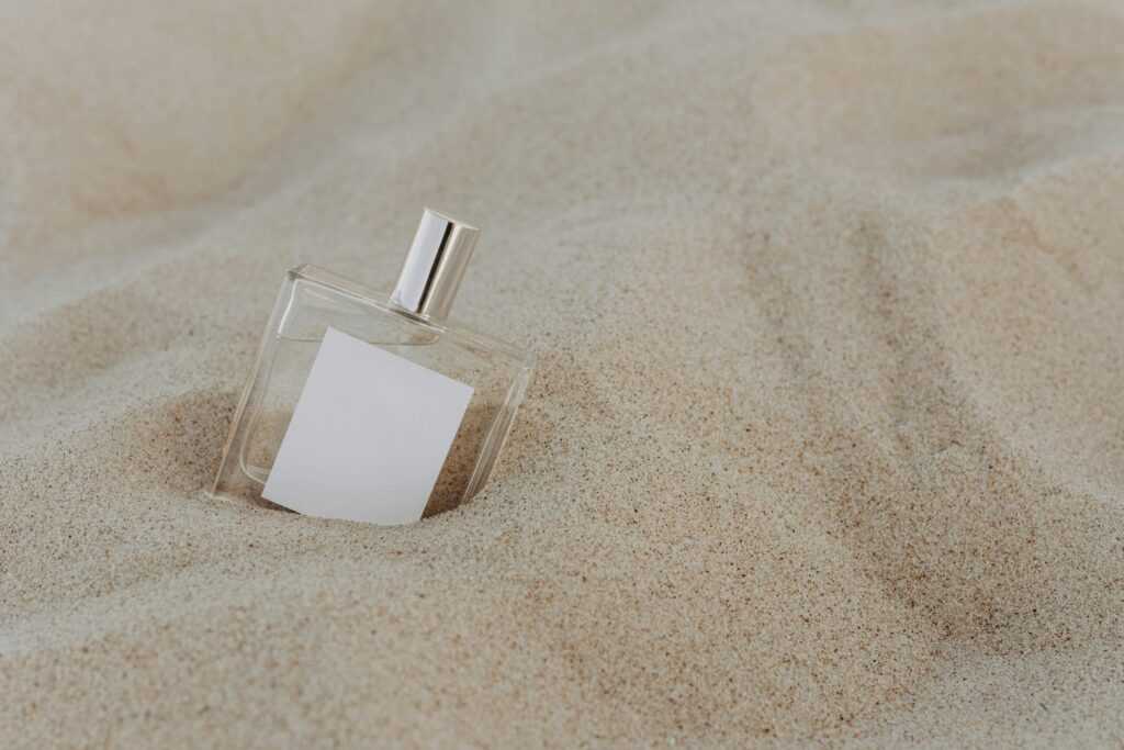 Minimalist perfume bottle on sandy background offering a fresh, elegant aesthetic.